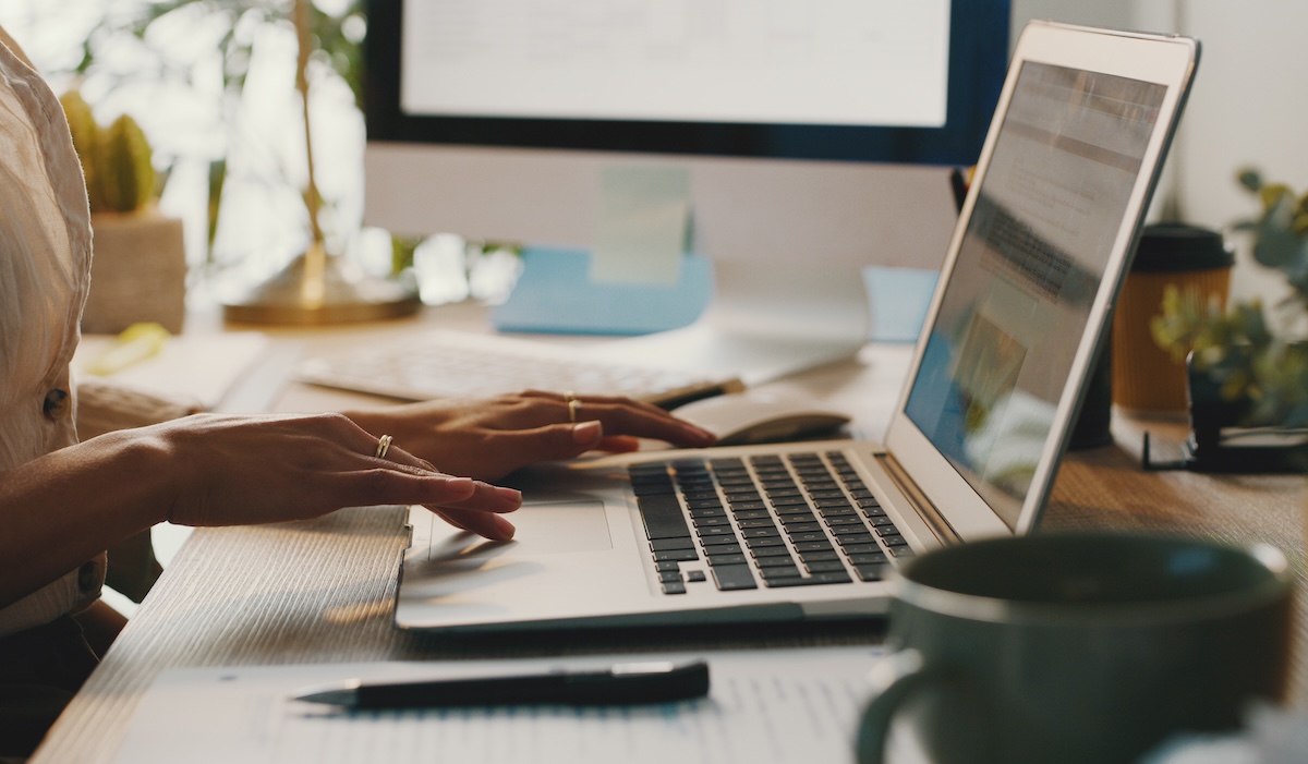 Primer plano recortado de una empresaria irreconocible sentada sola y usando su computadora portátil mientras trabaja en casa