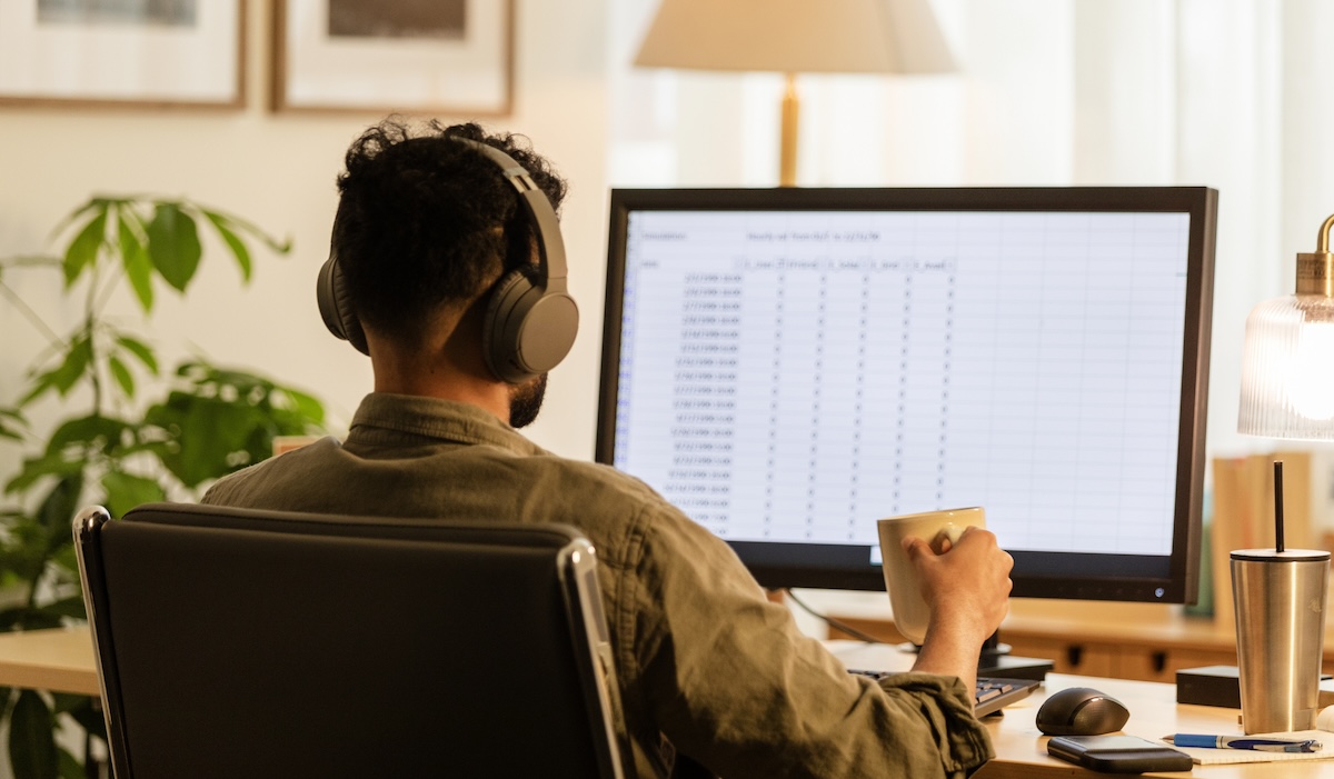 Unrecognizable young adult male works from home at the computer