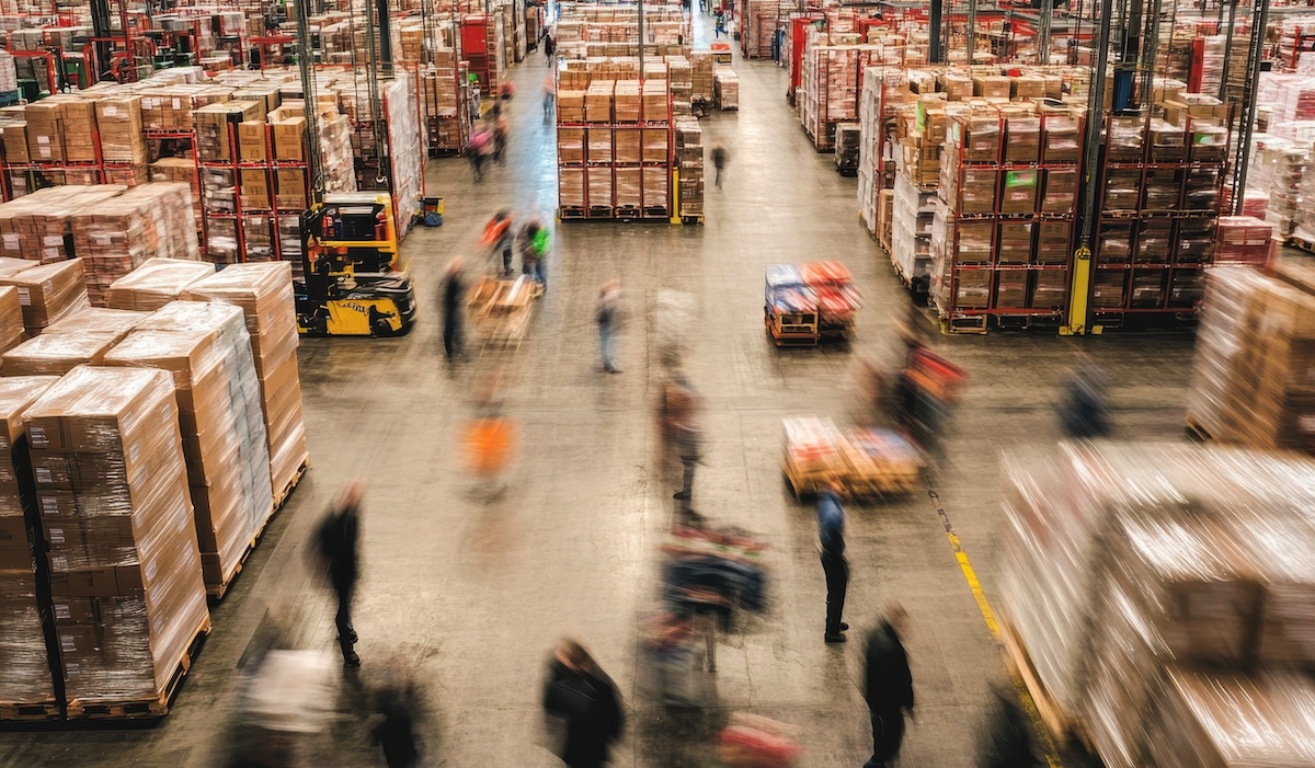 Warehouse bustling with activity as workers move pallets and goods efficiently throughout the large storage area