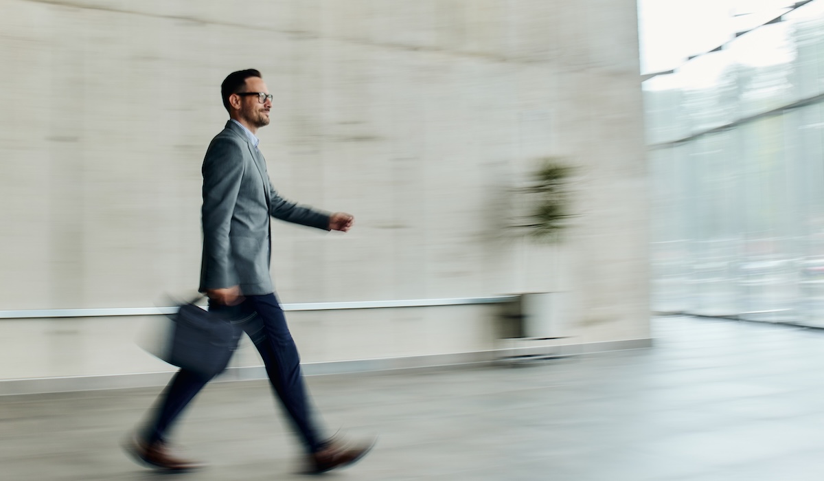 Smiling businessman walking in a hallway in blurred motion.